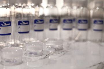 Small, transparent, plastic liquid bottles for plane traveling. Blank label with blue plane icon.