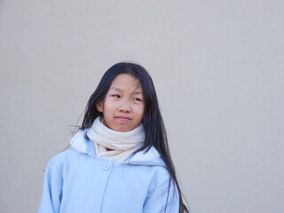 冬の屋外の壁のそばにいる可愛い小学生の女の子の姿