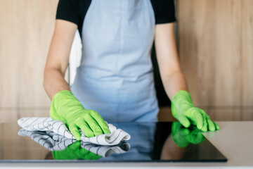 Modern kitchen with a woman cleaning the induction stove surface