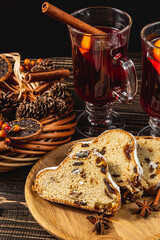 Two cups of mulled wine with spices, stollen on a plate on a wooden table