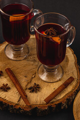 aromatic mulled wine with spices on a piece of wood on a black background