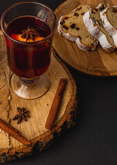 aromatic mulled wine with fresh stollen on a wooden plate on a black background