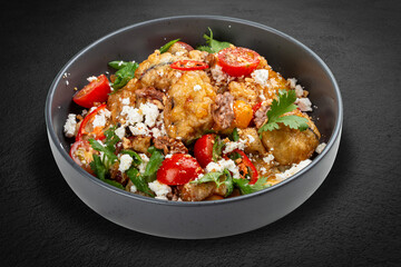 A vibrant salad featuring tempura-battered eggplant, juicy tomatoes, crunchy nuts, crumbled bryndza cheese, and fresh cilantro.