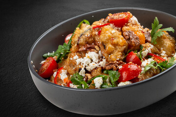 A vibrant salad featuring tempura-battered eggplant, juicy tomatoes, crunchy nuts, crumbled bryndza...
