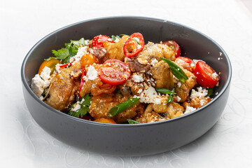 A vibrant salad featuring tempura-battered eggplant, juicy tomatoes, crunchy nuts, crumbled bryndza...