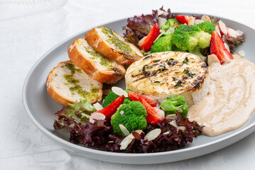 Grilled Camembert cheese served with creamy sauce and vegetables.
