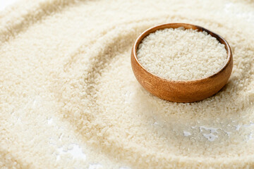 Bamboo bowl with round haired rice on white background with scattered grain. Healthy nutrition and light breakfast.