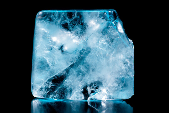 Ice cube isolated on black background, Abstract natural ice texture. Freezy ice surface. Blue icecube backdrop with cracks and scratches on frozen water, macro shot