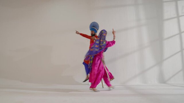 Sikh couple performing bhangra with khunda during Baisakhi celebration