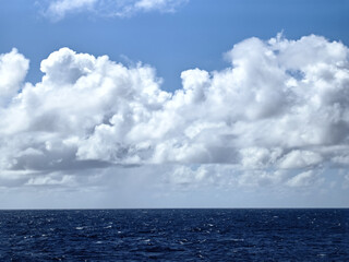 White fluffy clouds in a blue sky above the ocean