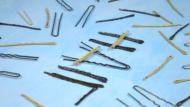 Hairpins and bobby pins of different shapes and colors are laid out on a blue background, composition
