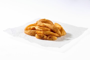 Golden and crispy potato wedges served on white paper, showcasing a rustic and appetizing snack.