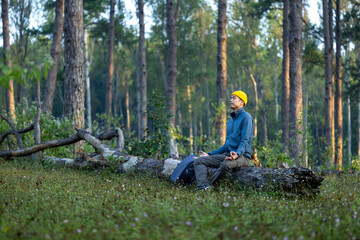 Asian man is relaxingly practicing meditation in pine forest to attain happiness from inner peace...