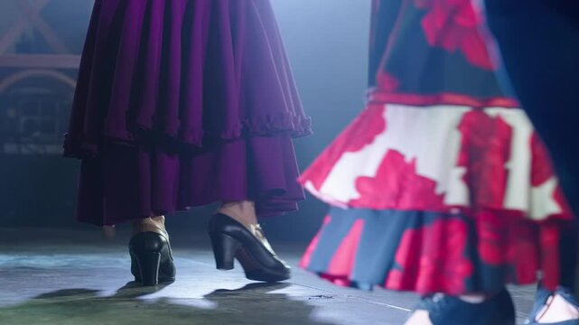 Women wearing traditional traje de flamenca dance on stage