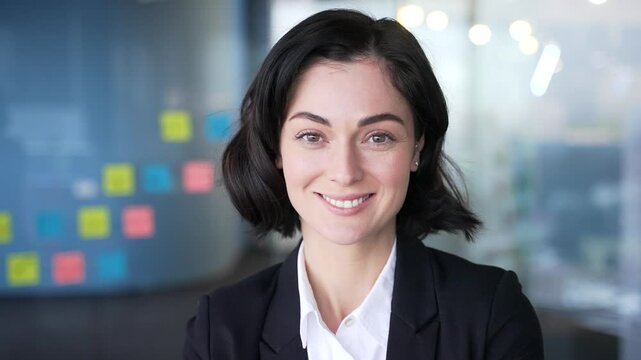 Smiling woman in professional business attire looking confidently at camera in office. Image conveys professionalism, confidence, and friendliness. Perfect for business, corporate, professional themes