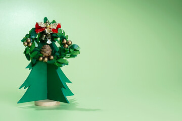 Closeup view of a Christmas tree miniature with a Christmas wreath on a colored background