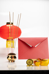 Incense on pot with envelope and red Chinese lantern hanging on white background