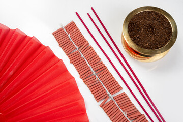 Incense with the pot and folding fan with a string of Chinese firecrackers on the rope on a white...