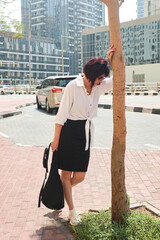 woman leaning against a tree on a noisy street, overcome with heartache, seeks help from passersby,...