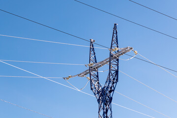 High-voltage wires and poles are covered with frost on a frosty winter day.
