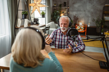 senior man host interviewer woman guest questions while record podcast