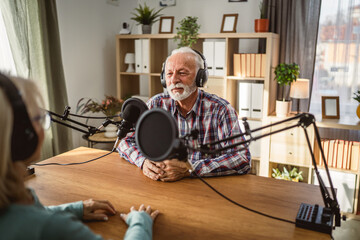 senior man host interviewer woman guest questions while record podcast