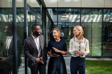 Professional team discussing business strategy outside modern office