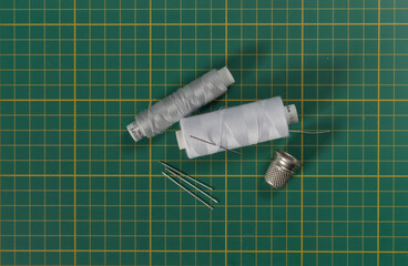 Threads, needles, timble on cutting matt