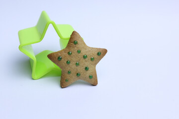 Green star shaped cookie cutter and gingerbread cookie on white background. christmas concept