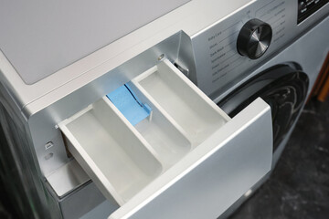 Close-up of open container for loading powder or gel for washing in washing machine in home laundry room.