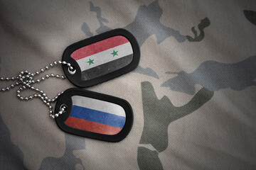 vintage army blank, dog tag with flag of syria and russia on the khaki texture background. military...