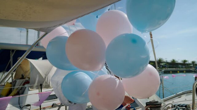 Woman unties bunch of colorful balloons from side of yacht