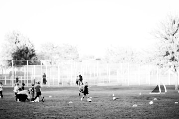 Purposefully blurred view of a youth soccer practice with multiple balls and a goal. 