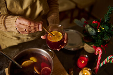 Preparing Warm Holiday Drink With Spices and Orange on Cozy Winter Evening