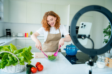 Young female chef creating delicious salad in bright home kitchen with vibrant daylight, capturing the joy of cooking