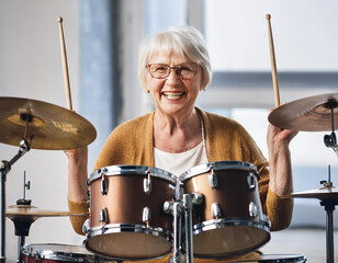 senior woman learning to play the drums at her home