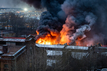 Careless handling of fire hazards. Firefighters extinguishing manufacturing warehouse. Burning...