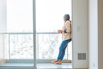 A woman is standing on a balcony looking out at the city