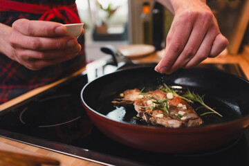 Mann brät sich ein Stück Fleisch zu Hause in der Pfanne