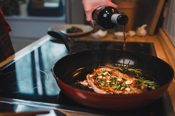 Mann brät sich ein Stück Fleisch zu Hause in der Pfanne