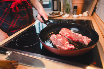 Mann brät sich ein Stück Fleisch zu Hause in der Pfanne