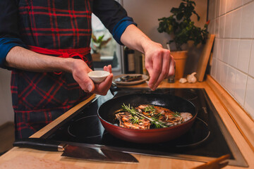 Mann brät sich ein Stück Fleisch zu Hause in der Pfanne