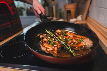 Mann brät sich ein Stück Fleisch zu Hause in der Pfanne