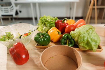 Colorful bell peppers, lettuce, and carrots are displayed on an office desk, ready for a healthy salad preparation