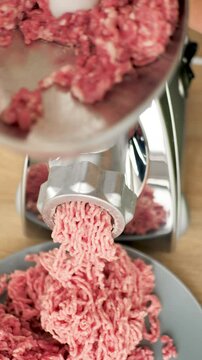 Vertical: Reprocessing minced meat using an electric meat grinder. Cooking semi-finished meat products at home. Using a finer grate in a meat grinder for better grinding