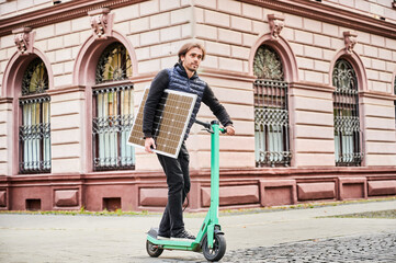 Man rides electric scooter while carrying solar panel. Integration of solar power as sustainable...