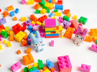 Colorful plastic building blocks and toy bunny on a white background.