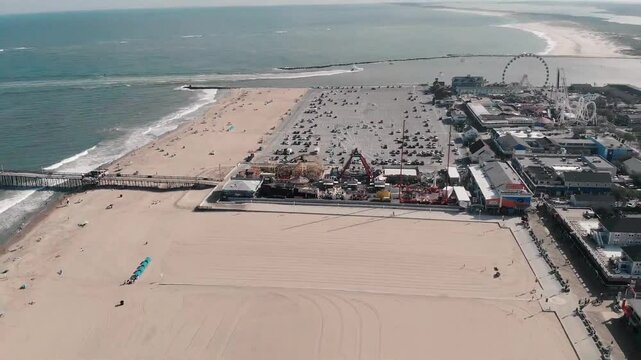 Aerial footage of Ocean City, USA, featuring the town's beach, sea, vibrant city streets, highways, buildings, and people enjoying the coastal lifestyle. Perfect for showcasing urban, tourism, and bea