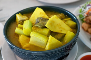 Yellow curry with fish, bamboo shoot and green taro (aaw dip) thai southern style food on table.