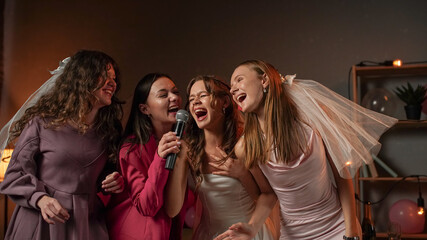Group of young women friends and bride celebrating bachelorette party at home, bride and...